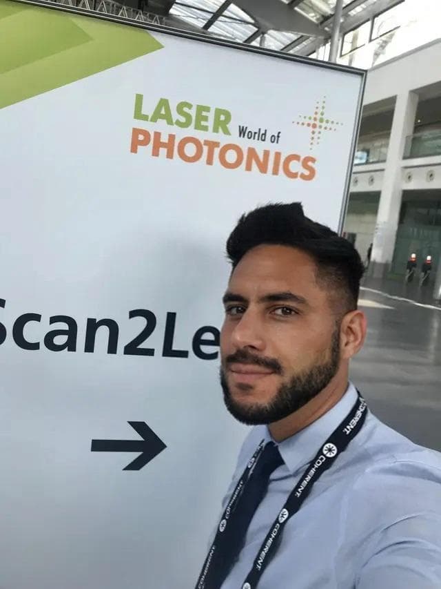 Ramon Lochner beside a Laser World of Photonics sign in the entrance hall at Messe München.